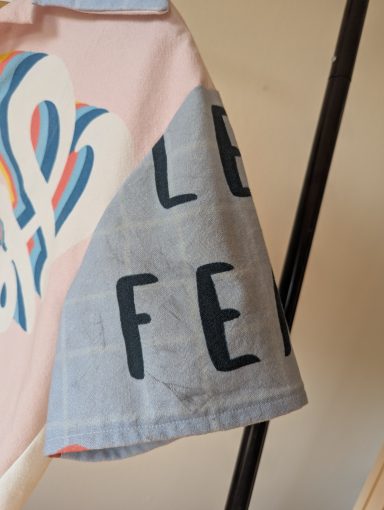 Ärmelansicht der Retro Bluse mit buntem Regenbogen und "Hey" Schriftzug