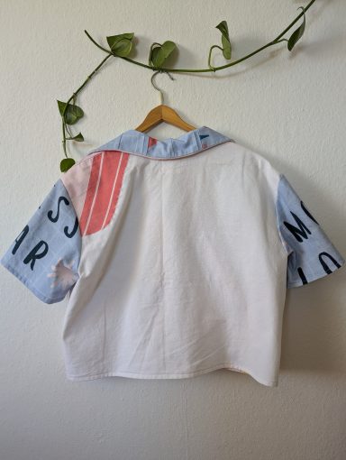 Rückenansicht der Retro Bluse mit buntem Regenbogen und "Hey" Schriftzug