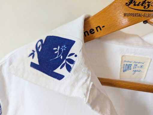 Bluse "Tea Time" in weiß und blau. Fokus auf Kragendetail mit Teetasse
